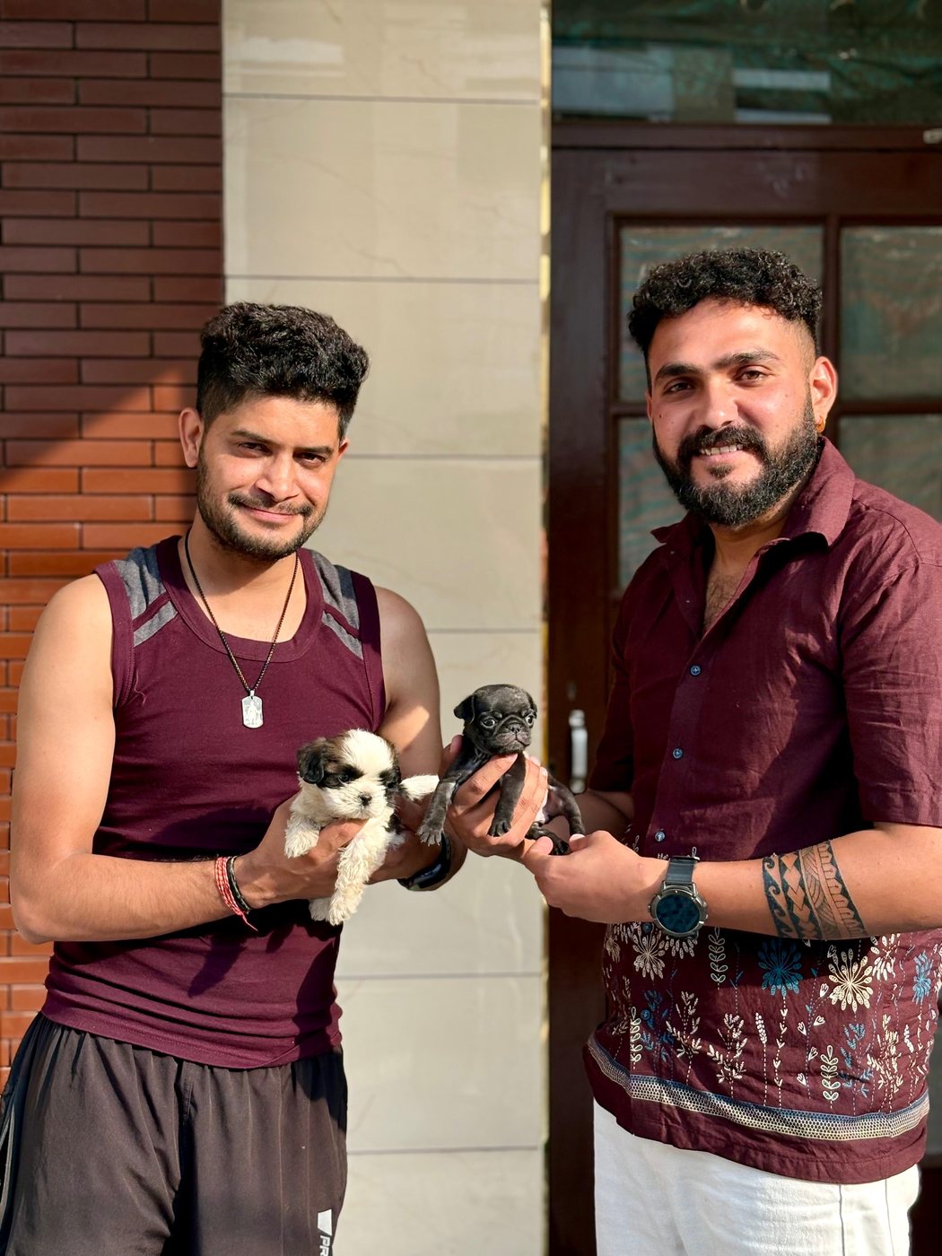 The Sharma Dog Kennel team with two playful puppies